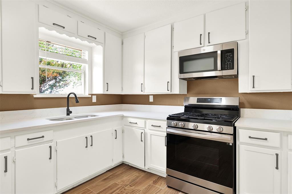 Kitchen with light wood-type flooring, sink, stainless steel appliances, and white cabinets