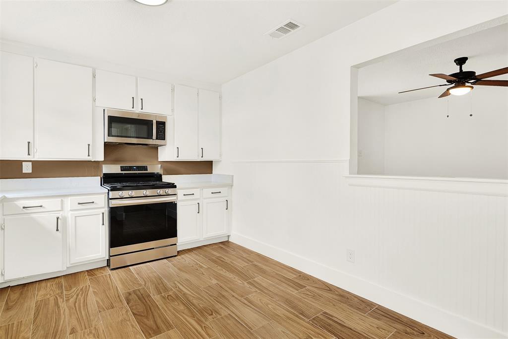 Kitchen featuring ceiling fan, appliances with stainless steel finishes, white cabinetry, and light hardwood / wood-style flooring