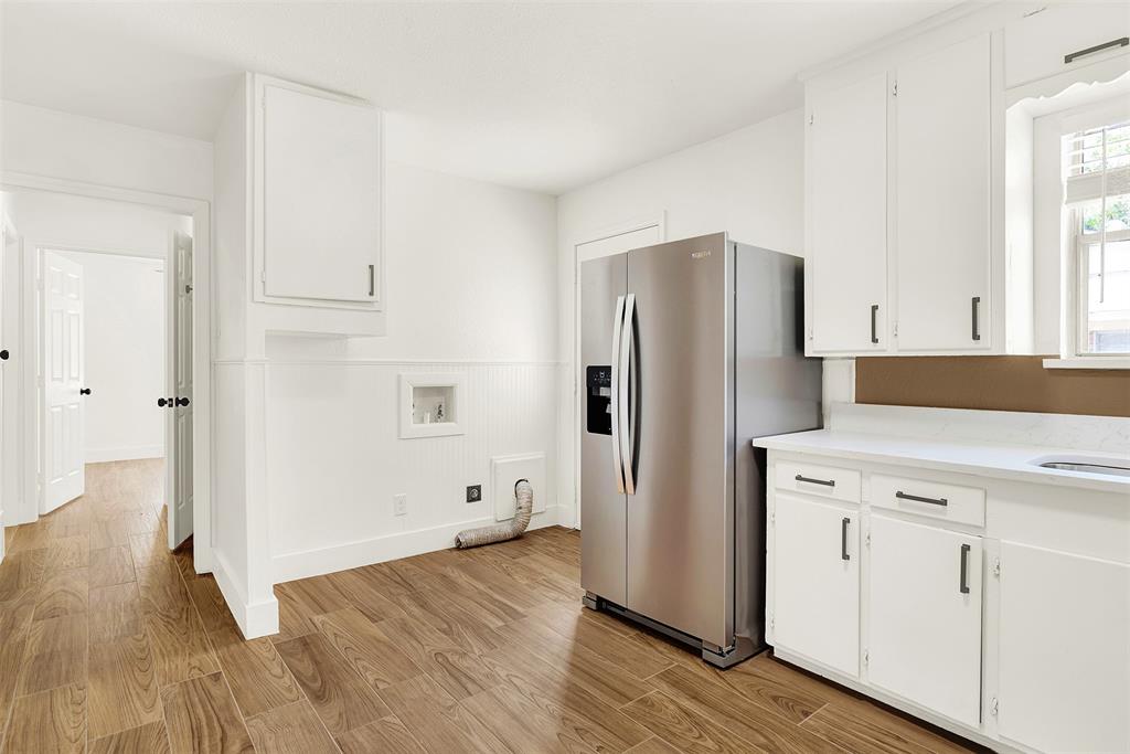 Kitchen featuring light wood-type flooring, stainless steel fridge, and white cabinets