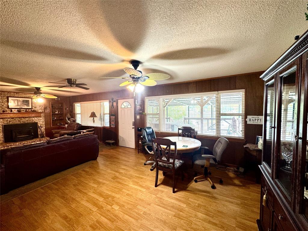 Wood-finish flooring, wood paneling, multiple ceiling fans, and a brick-surround fireplace with a hearth