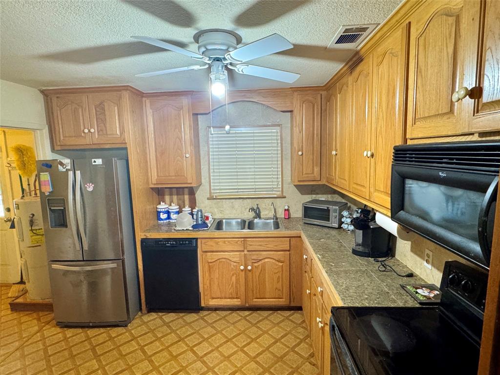 Kitchen featuring wood cabinetry, laminate countertops, a double basin sink, and a ceiling fan