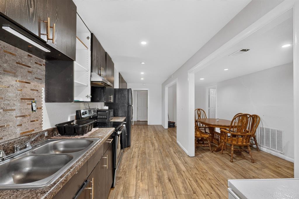 Kitchen featuring dark wood-finish cabinetry, a dual basin stainless steel sink, and a tiled backsplash
