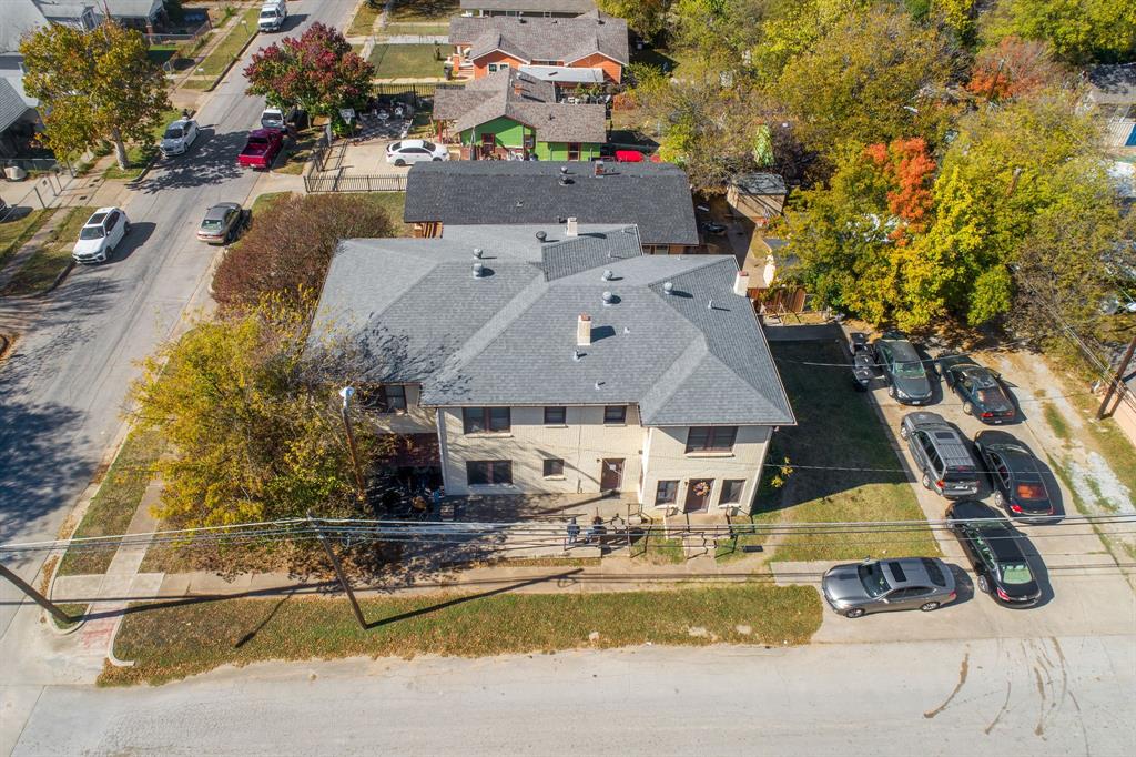 Two-story exterior with a gray shingle roof, paved driveway, and established trees