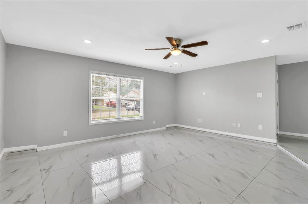 Spacious room featuring large format tile flooring, crisp white baseboards, and neutral gray walls