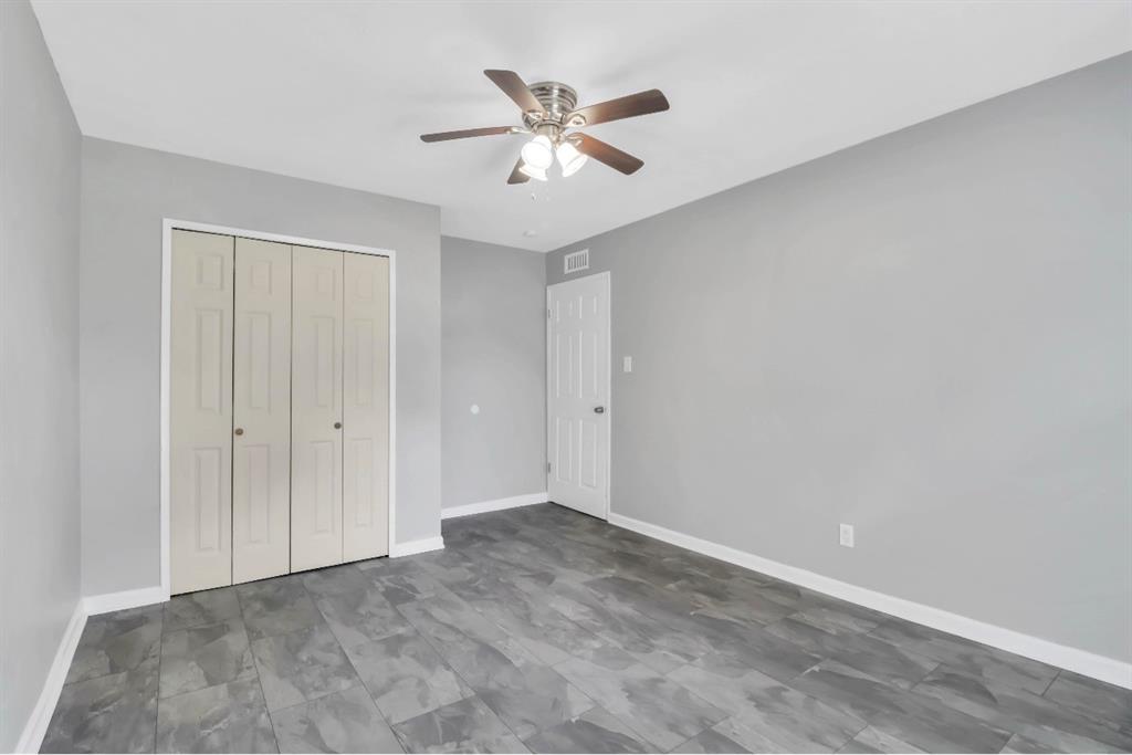Spacious room featuring wood-finish flooring, a ceiling fan with integrated lighting, a bi-fold closet, and a white interior door