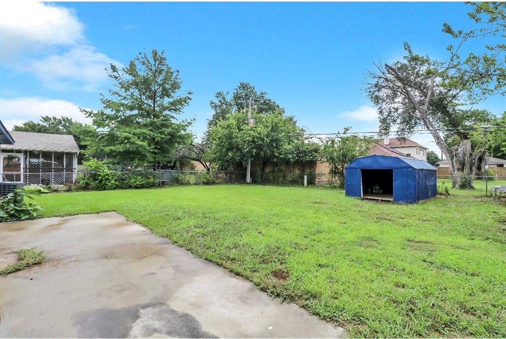 Expansive backyard featuring a concrete patio, a blue metal shed, and a screened porch