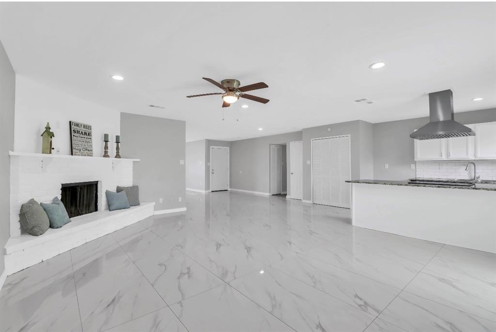 Spacious interior with large format tile flooring and a white brick fireplace
