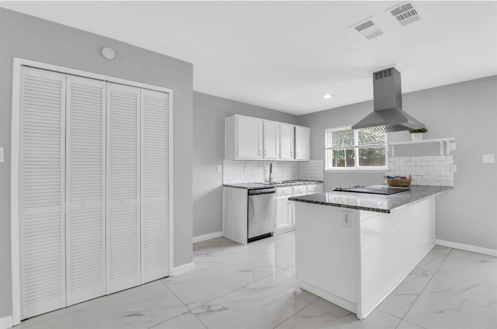 Kitchen featuring a central island with a built-in cooktop, stainless steel range hood, white cabinetry, and a subway tile backsplash