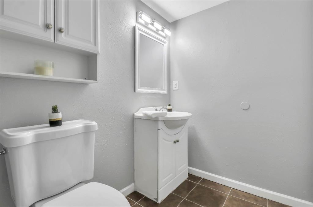 Bathroom featuring a white vanity with integrated sink, coordinating mirror, and overhead vanity lighting