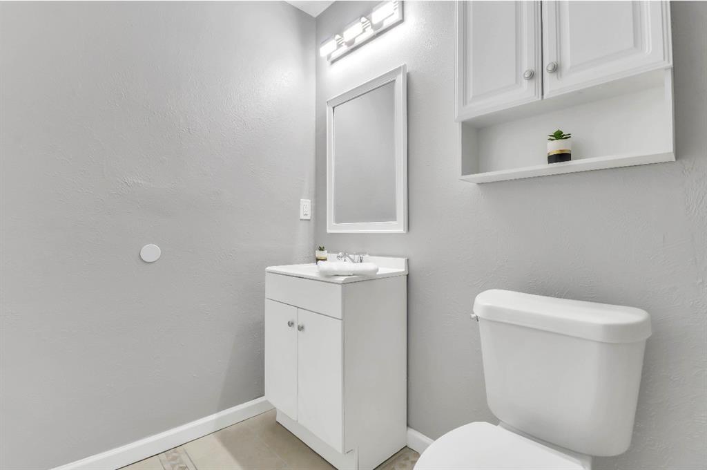 Bathroom featuring a white vanity with integrated sink, framed mirror, and chrome-finish light fixture