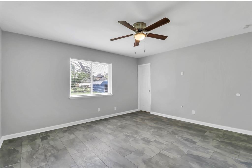 Spacious room featuring gray walls, wood-finish flooring, and white baseboards