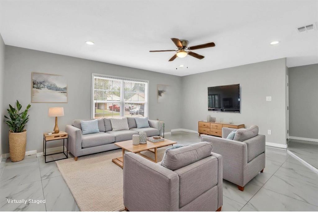 Living area featuring light gray walls, large window, ceiling fan with light fixture, recessed lighting, and large format tile flooring