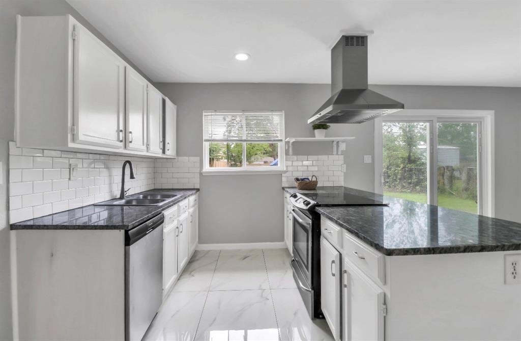 Modern kitchen featuring white cabinetry, dark stone countertops, subway tile backsplash, stainless steel appliances, and a sliding glass door