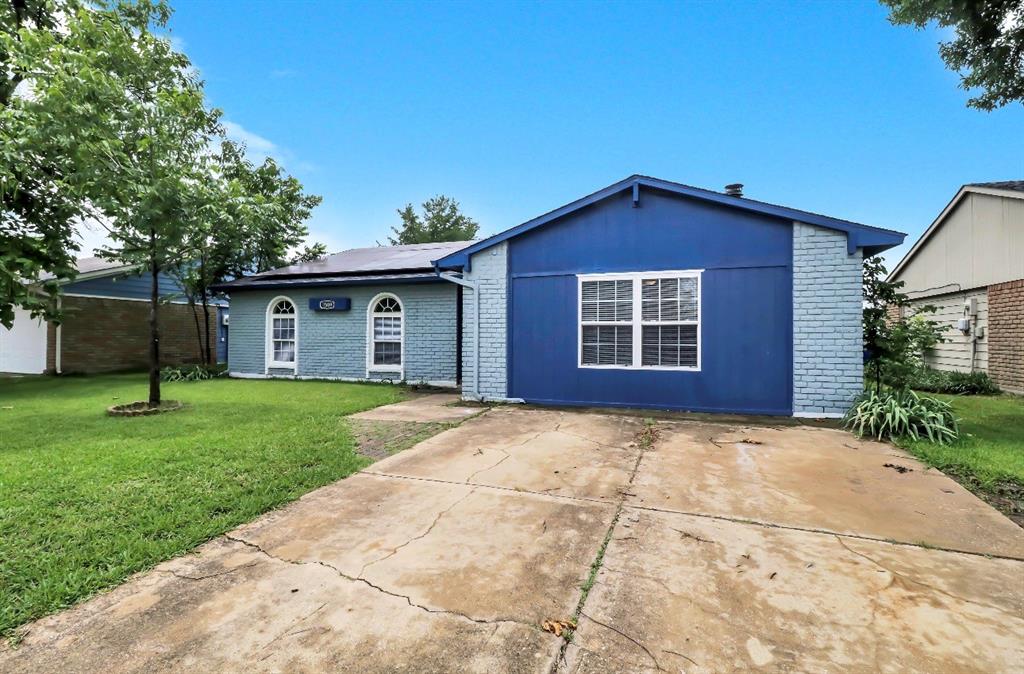Blue exterior with white trim, featuring a concrete driveway and a manicured green lawn