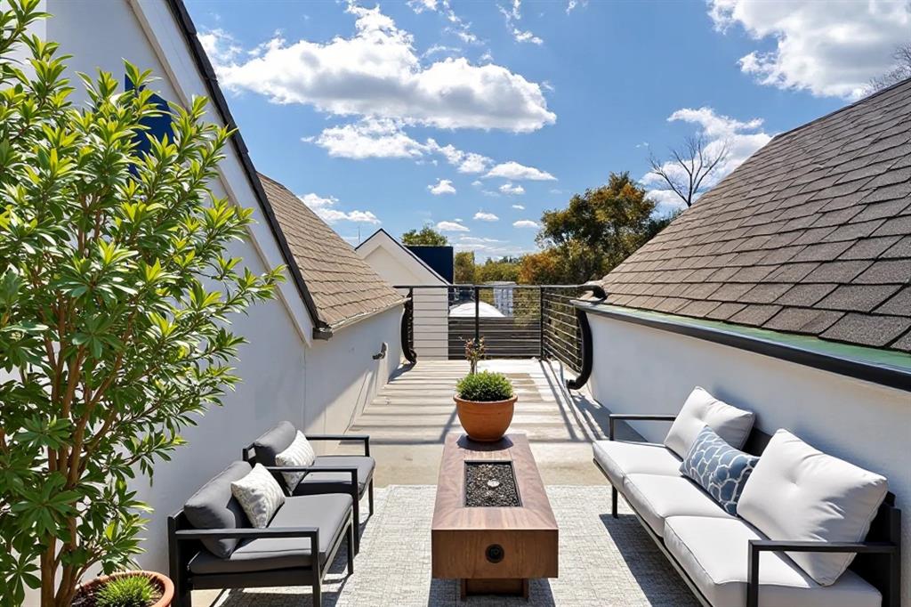 Rooftop deck featuring a horizontal slat railing, wood-finish fire pit table, and a neutral-toned hardscaping