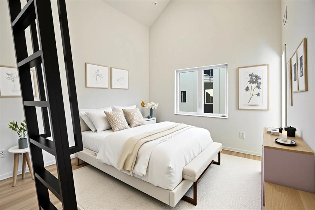 Vaulted ceiling with light-toned walls, wood-finish flooring, and a large window