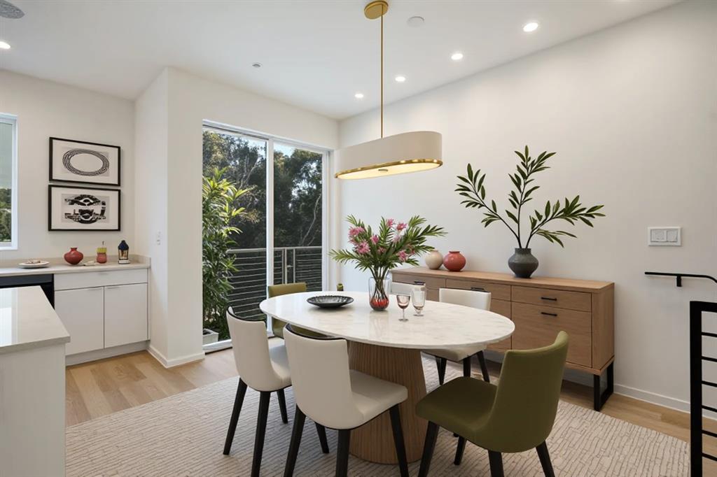 Dining area featuring light wood-finish flooring, a contemporary oval dining table, a linear pendant light fixture, and a built-in wood cabinet