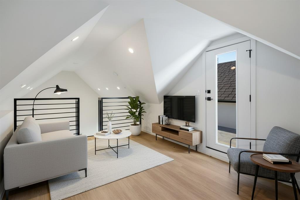 Sloped ceilings with recessed lighting, wood-finish flooring, a full-light door, and black horizontal railings