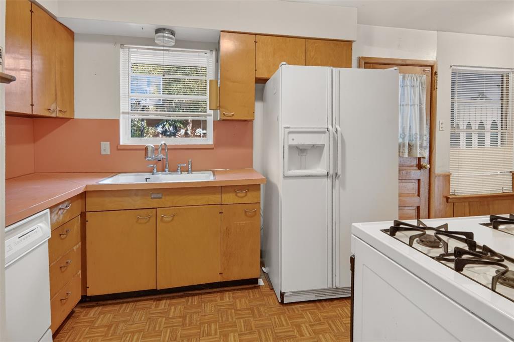 L-shaped kitchen with wood-finish cabinetry, a white double-door refrigerator, and a white gas range