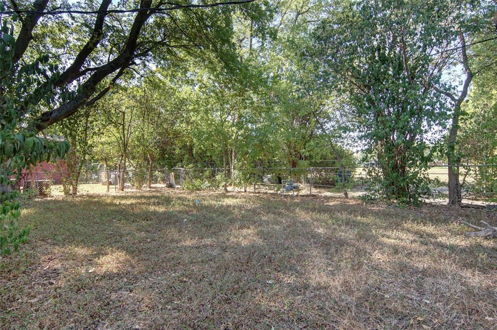 Expansive yard with mature trees, established foliage, and perimeter fencing