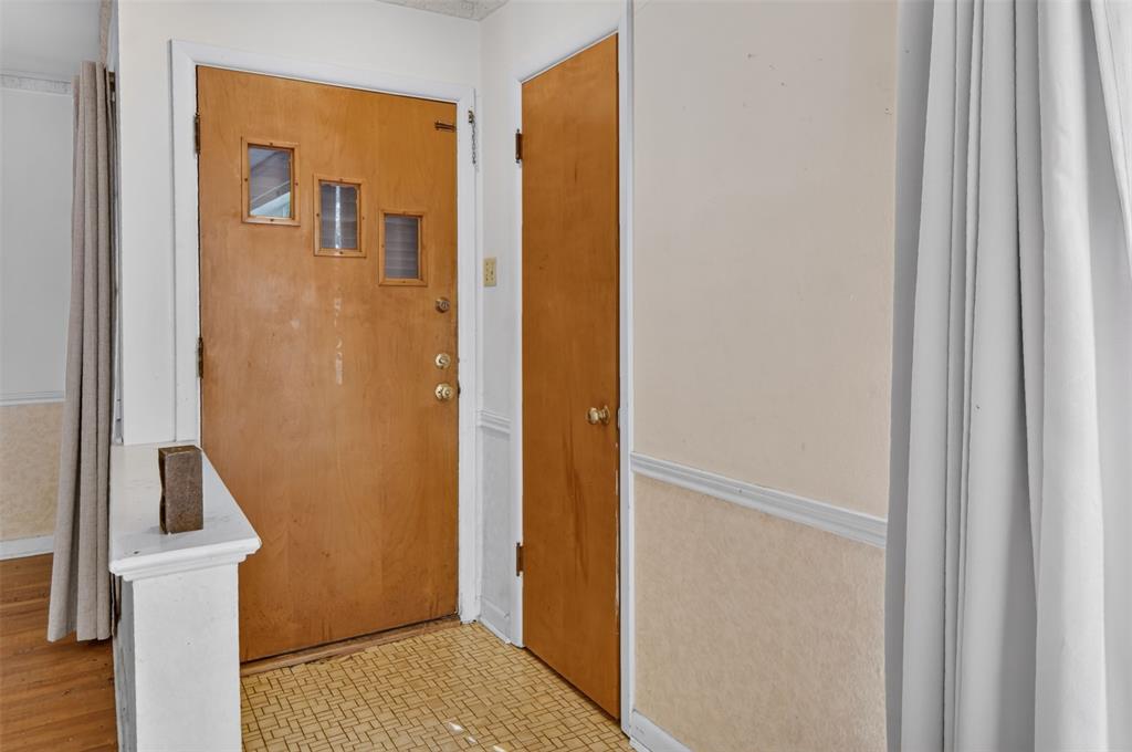 Hardwood entry door with three inset windows, patterned floor tiling, and neutral wall tones Hardwood entry door with three inset windows, patterned floor tiling, and neutral wall tones