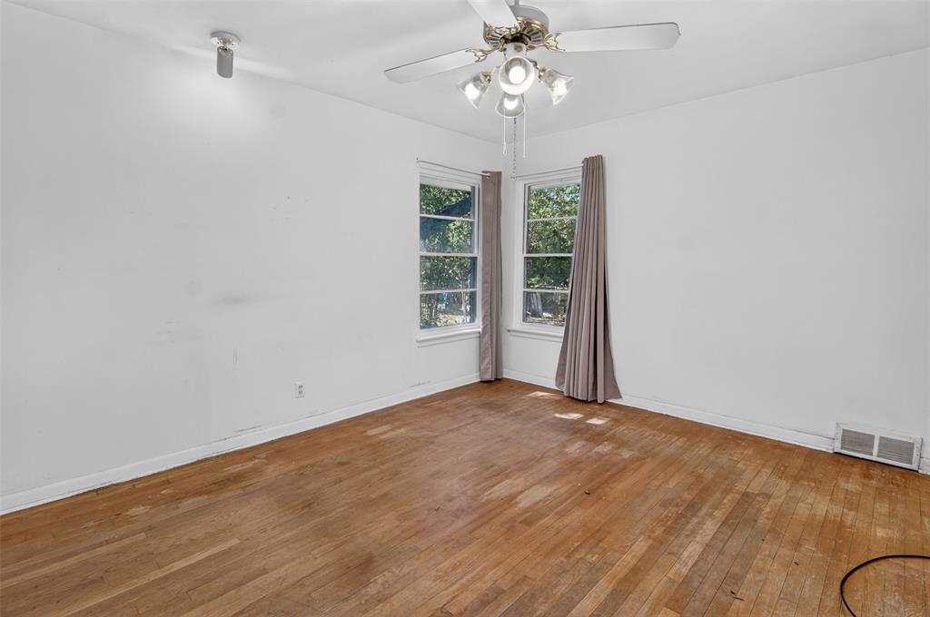 Hardwood flooring, two windows, ceiling fan, white walls, and a wall-mounted light fixture