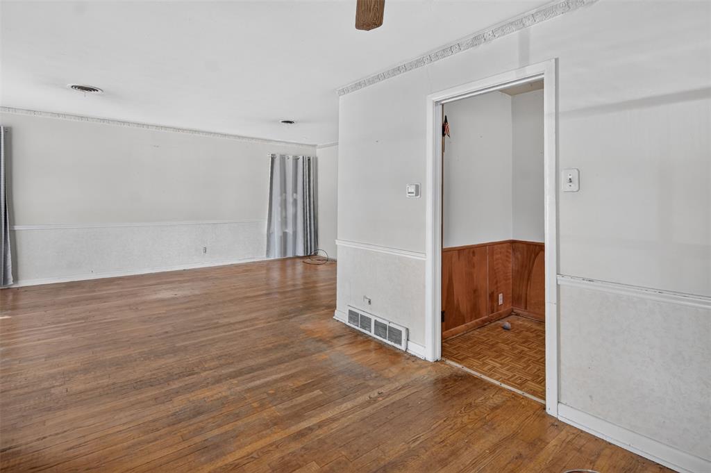 Wood-finish flooring, white walls, decorative crown molding, and white chair rail with textured panels