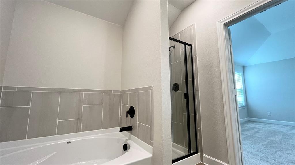 Corner soaking tub with matte black fixtures, an adjacent walk-in shower with a glass enclosure, and modern tile surround