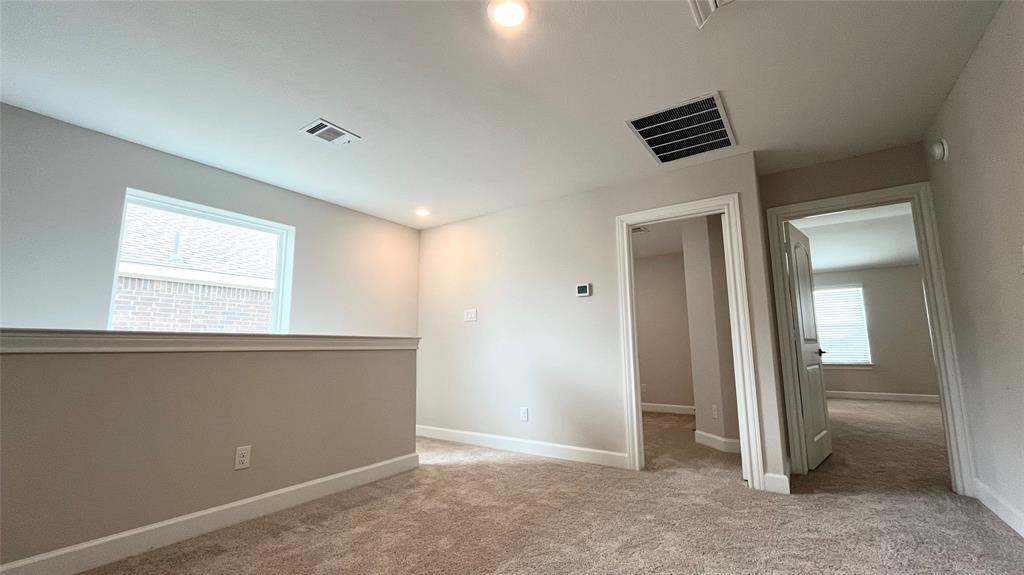 Carpeted upper-level landing with neutral wall tones, recessed lighting, and a white framed window