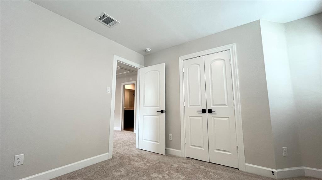 Carpeted flooring with light-toned walls, white trim, and a white interior door with black hardware