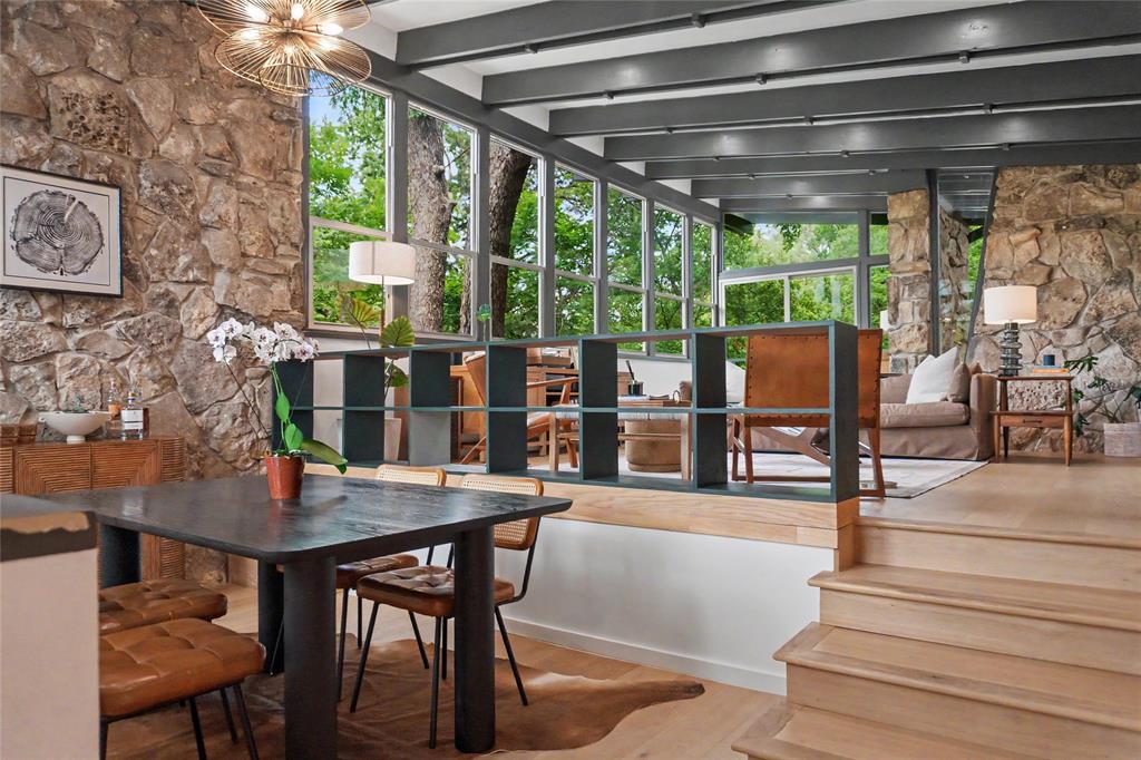 Natural stone accent walls, exposed ceiling beams, expansive floor-to-ceiling windows, light wood-finish flooring, and built-in grid shelving Natural stone accent walls, exposed ceiling beams, expansive floor-to-ceiling windows, light wood-finish flooring, and built-in grid shelving