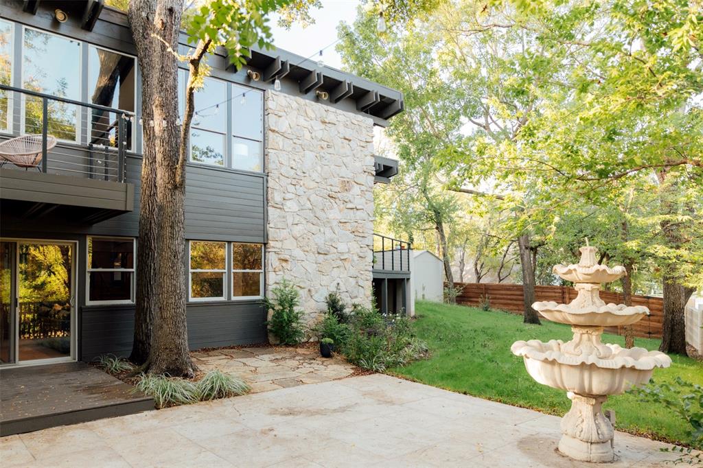 Side patio with tiered fountain, stone wall, and lawn