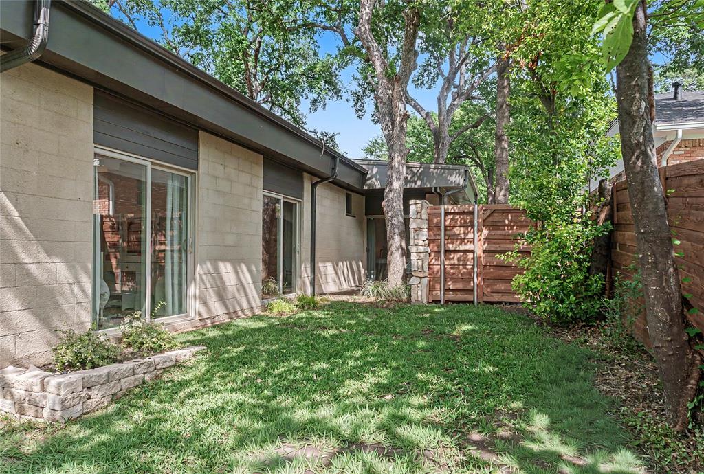 Backyard framed by mature trees and an American cedar fence