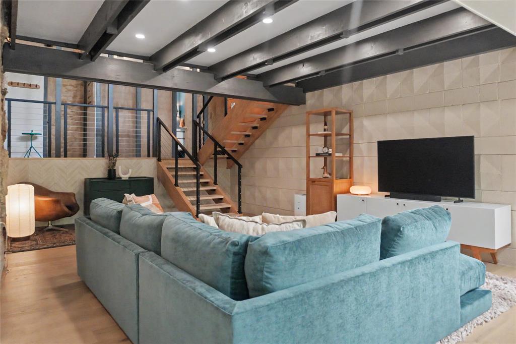 Lower level living room with exposed ceiling beams, geometric textured wall panels, and perfect for movie night