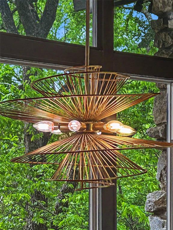 Brass spiraled chandelier against a wall of foliage