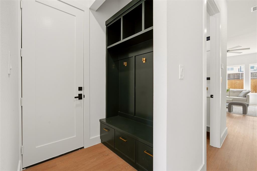 Built-in dark cabinetry with integrated bench seating, brass-finish hardware, and storage cubbies Built-in dark cabinetry with integrated bench seating, brass-finish hardware, and storage cubbies