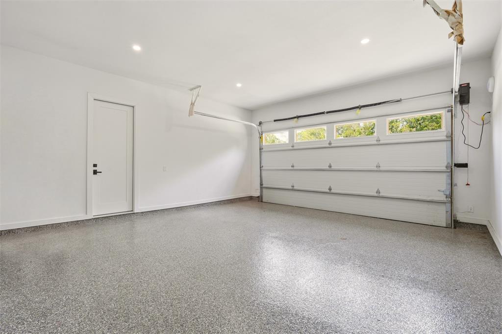 Epoxy-coated flooring, recessed lighting, and a white overhead garage door with upper windows