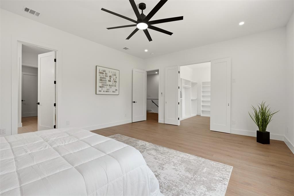 Spacious room featuring wood-finish flooring, a modern black ceiling fan, recessed lighting, and a built-in walk-in closet with shelving