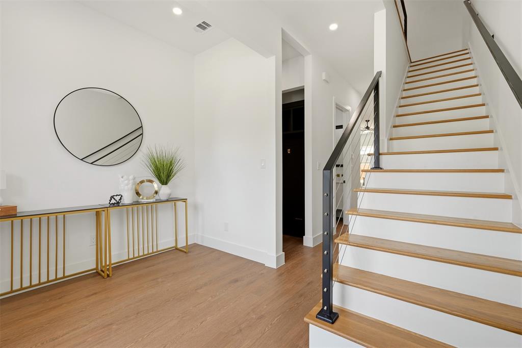 Wood-finish flooring, recessed lighting, white walls, and a staircase with wood treads and a cable railing system Wood-finish flooring, recessed lighting, white walls, and a staircase with wood treads and a cable railing system