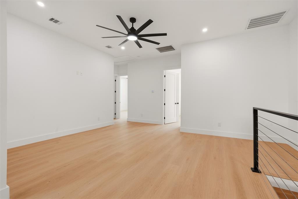 Wood-finish flooring, recessed lighting, ceiling fan, white walls, and modern metal railing