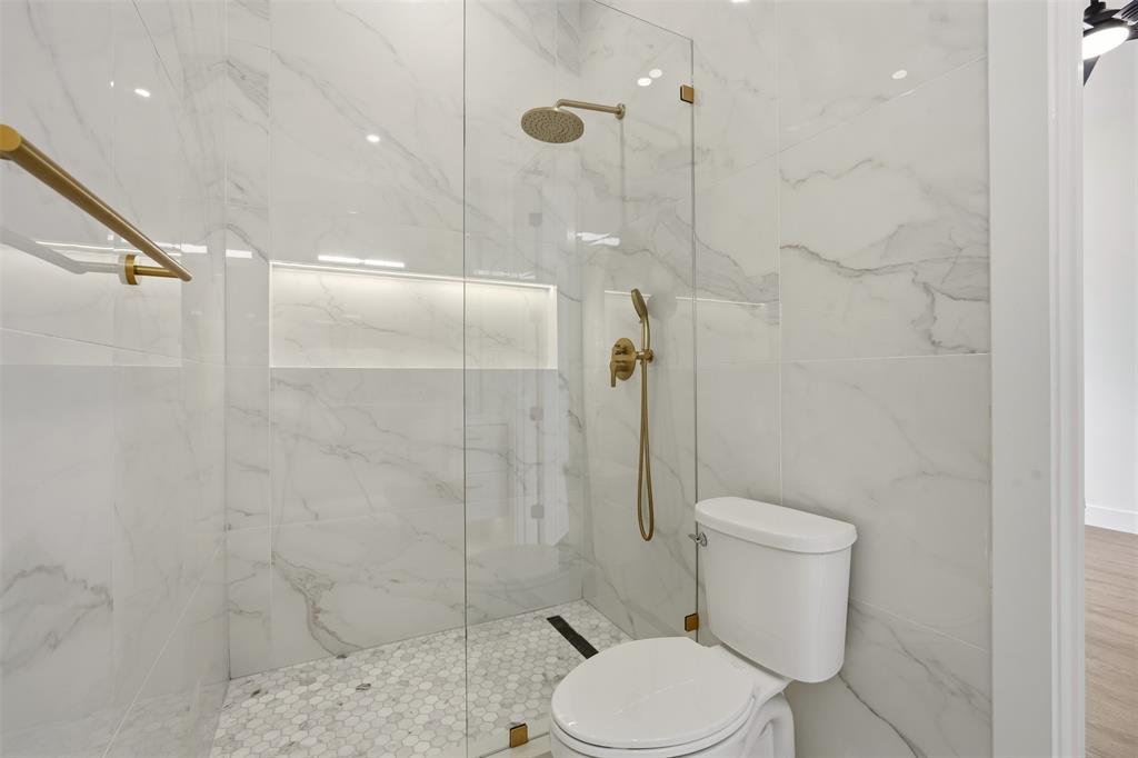 Walk-in shower with full-height large format wall tile, rain shower head, and built-in niche