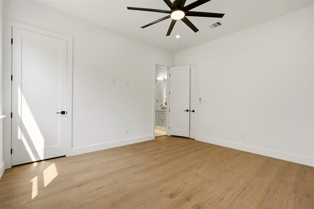 Wood-finish flooring, crisp white walls, contemporary ceiling fan, modern interior doors with matte black hardware, and bright recessed lighting