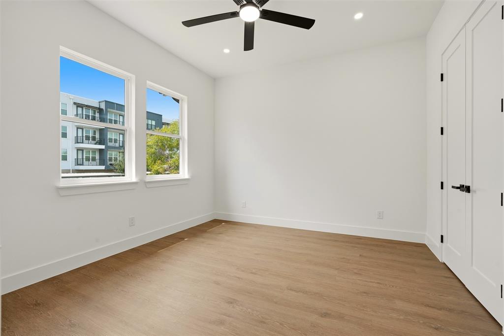 Two double-hung windows with white trim, wood-finish flooring, a contemporary ceiling fan, recessed lighting, and a paneled door with matte black hardware