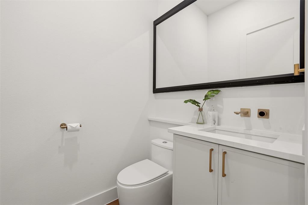 White vanity with integrated sink, gold-tone hardware, and a wall-mounted faucet White vanity with integrated sink, gold-tone hardware, and a wall-mounted faucet