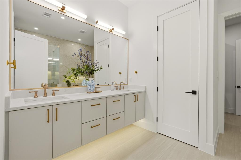 Dual vanity with integrated sinks, quartz countertop, contemporary gold-tone hardware, and under-cabinet lighting