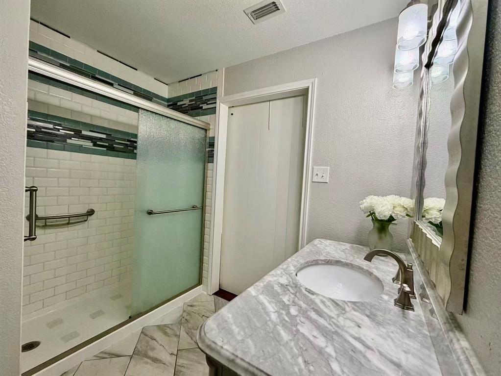 Shower with subway tile surround and decorative accent band, sliding glass enclosure, and grab bar