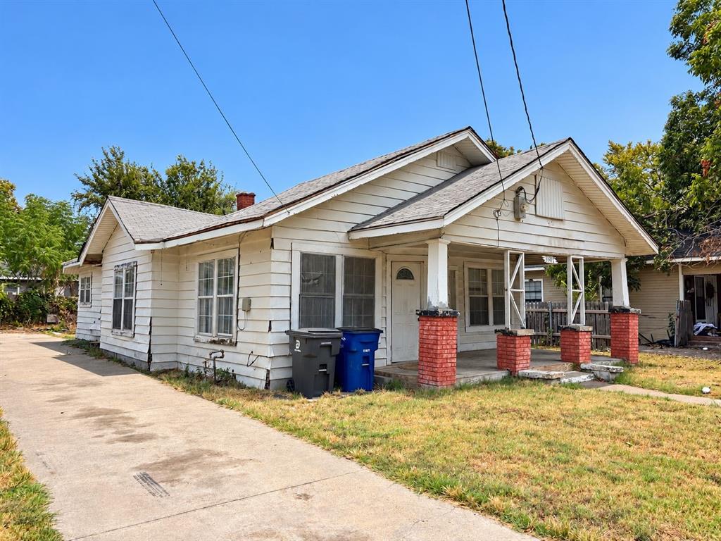 Single-story residence featuring a covered front porch with brick pillars, white siding, and a concrete driveway