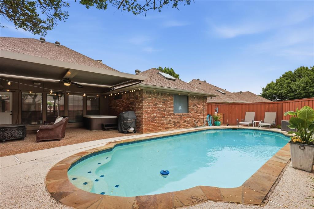 Inviting backyard featuring a swimming pool with stone coping, a covered patio, a hot tub, and a privacy fence