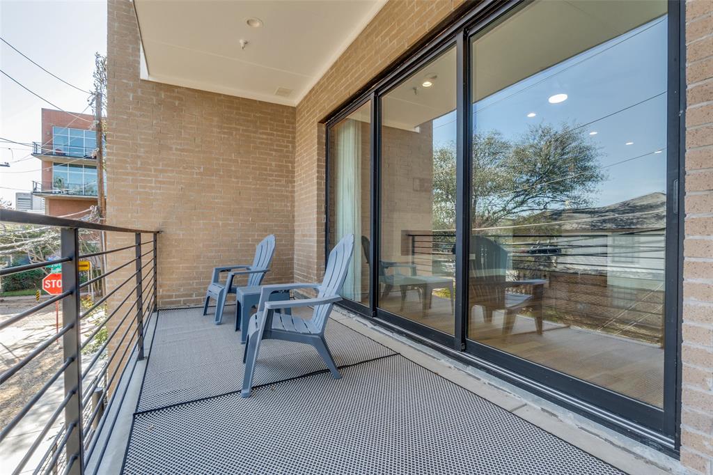 Balcony featuring brick exterior, black metal railing, and large sliding glass doors