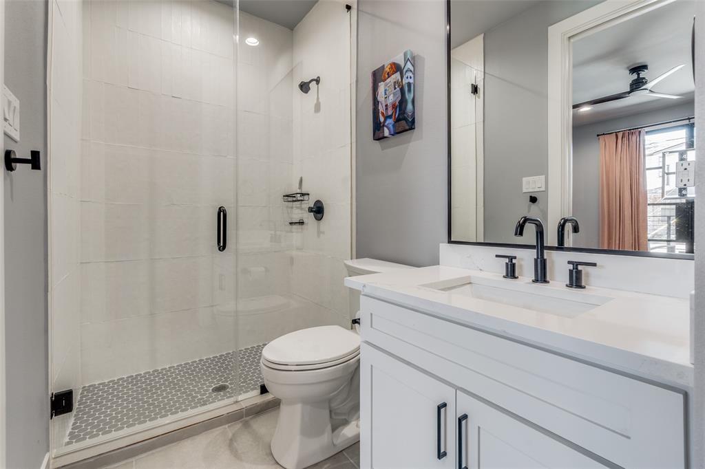 Walk-in shower with clear glass enclosure and mosaic tile floor